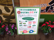 植物プラスチック導入をPRする看板と堆肥で育った花